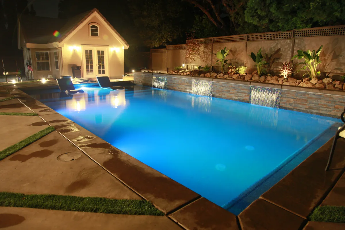 Rectangular pool deck jets poolhouse night by Pinnacle Pools and Landscape, Sacramento CA